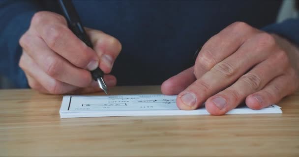 Mężczyzna wypisujący czek, aby zapłacić za usługi.Podpisanie czeku na stole - Materiał filmowy, wideo