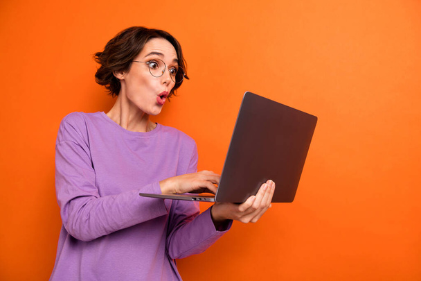 Photo of impressed person hold use wireless netbook pouted lips isolated on orange color background. - Фото, зображення