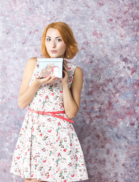Beautiful red-haired girl with gift box in hands. Portrait of beautiful young girl in a short dress - Foto, Imagem