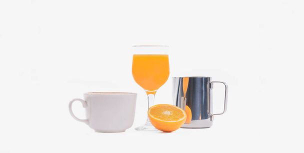 Orange juice surrounded by a cup of coffee, an orange slice and a milk frothing pitcher on a light background. Selective focus. Breakfast concept. - Foto, afbeelding