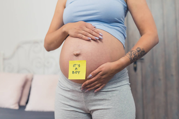schwangere Frau mit einem klebrigen Zettel mit der Aufschrift Junge auf ihrem Bauch, Nahaufnahme. Hochwertiges Foto - Foto, Bild
