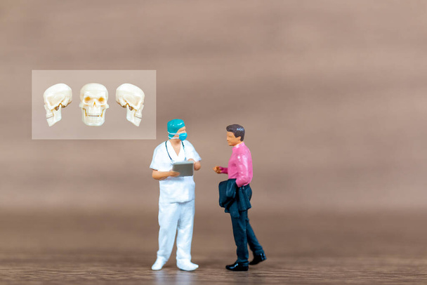 Miniatuur mensen patiënten worden besproken door een orthopedisch arts. Gezondheidszorgconcept - Foto, afbeelding