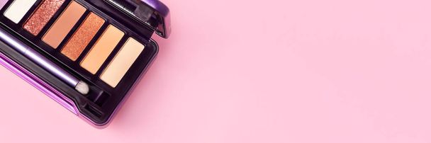 Πολύχρωμο παλέτα σκιά ματιών σε ροζ φόντο με αντίγραφο banner χώρο. Χρωματική παλέτα σκιών ματιών με πινέλο. Ευρεία πανοραμική κεφαλίδα - Φωτογραφία, εικόνα