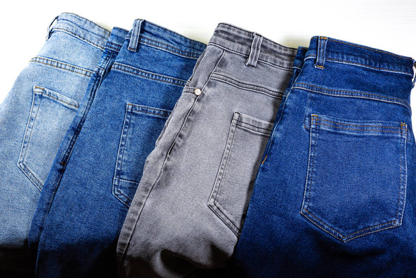 Verschillende kleuren van Old vintage Grey en Blue hipster jeans. Denim doek textuur achtergrond. Natuurlijke weefsels. - Foto, afbeelding