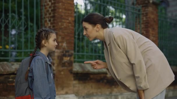 Mothes stands and talks with child gives recommendations on the street before lessons. Female adult emotional jest in conversation with kid - Filmati, video