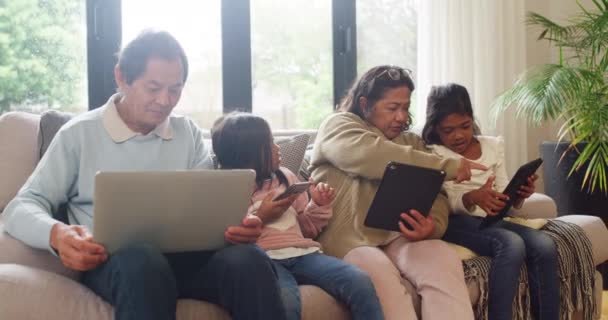 Happy family bonding with kids while using a laptop, digital tablet and phone with the home wifi. Children playing on multimedia devices, watching videos together in grandparents home on the weekend. - 映像、動画