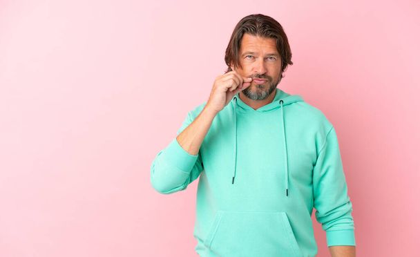 Senior dutch man isolated on pink background showing a sign of silence gesture - Foto, Bild