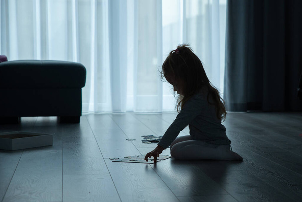 little girl is putting puzzles on the floor in the living room - Foto, Imagem
