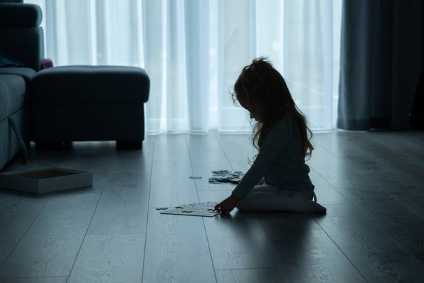 little girl is putting puzzles on the floor in the living room - Foto, immagini