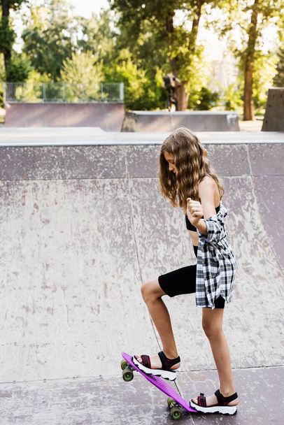 Teenager girl ready for ride on penny board on skateboard park playground. Sports equipment for kids. Extreme lifestyle - 写真・画像