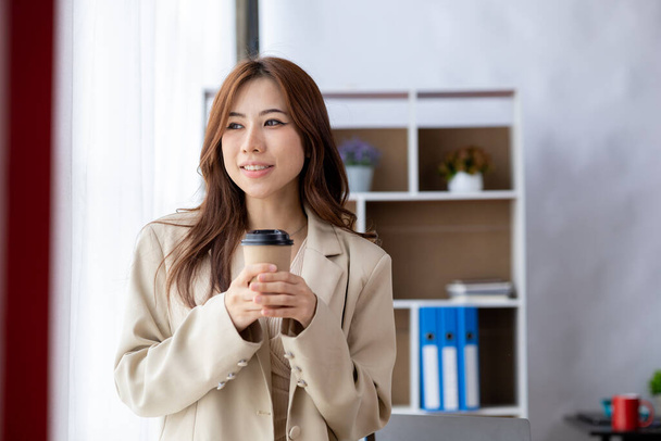 Businesswoman holding a paper cup of coffee, a young businesswoman and a young executive founded a startup that has consistently made high profits. Concept of young businesswoman and startup company. - Valokuva, kuva