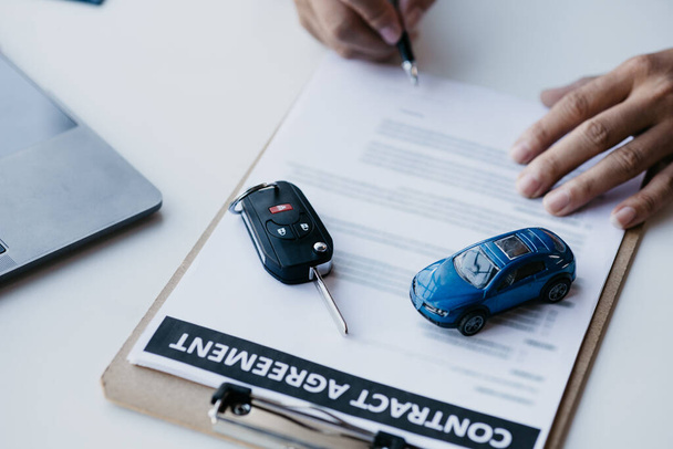 The salesperson is explaining the details of the purchase contract to the customer before agreeing to the contract, selling the car, selling the car at a major dealer. Vehicle sales concept. - Photo, image