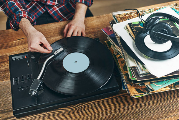 Man listening to music from vinyl record. Playing music from analog disk on turntable player. Enjoying music from old collection. Relaxing at home. Retro and vintage. Music passion - Фото, зображення