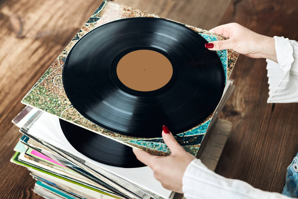 Playing vinyl records. Listening to music from vinyl record player. Retro and vintage music style. Woman holding analog LP record album. Stack of old records. Music collection. Music passion - Fotoğraf, Görsel