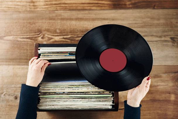 Playing vinyl records. Listening to music from vinyl record player. Retro and vintage music style. Woman holding analog LP record album. Stack of old records. Music collection. Music passion - Fotoğraf, Görsel
