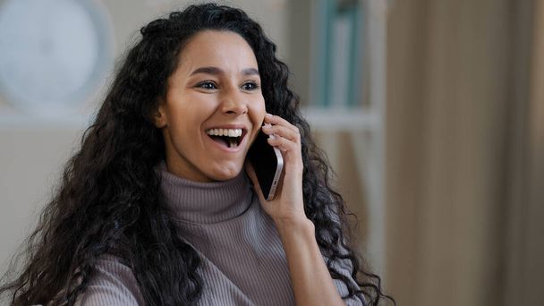 Vrij Arabisch glimlachend meisje jonge dame praten via mobiele telefoon genieten van draadloos gesprek vertellen roddel geschokt blij gelukkig duizendjarige vrouw blij horen goed nieuws positieve feedback blij voor succes deal - Foto, afbeelding
