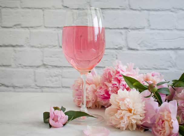 Een glas wijn bloem pioen op een lichte achtergrond - Foto, afbeelding