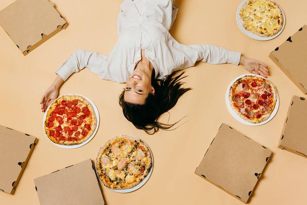 Foto en estilo pop art. Una chica con mucha pizza sobre un fondo de color - Foto, imagen