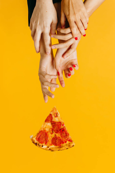 Creatief concept reclame fast food. Handen reiken naar een stuk pizza. - Foto, afbeelding