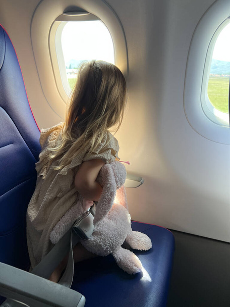 Little girl looks out the window of an airplane. Back view. High quality photo - Foto, immagini