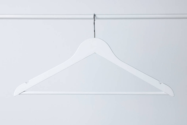 White clothes hanger on metal rail against light background - Fotoğraf, Görsel
