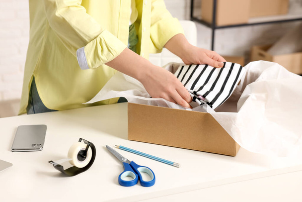 Seller packing clothes into cardboard box at workplace, closeup - Photo, image