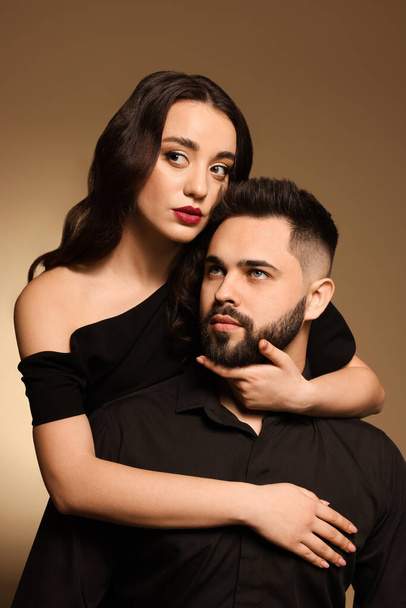 Handsome bearded man with sexy lady on light brown background - Foto, Bild