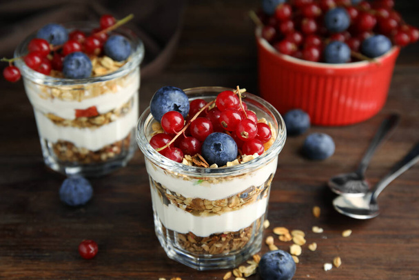 Delicious yogurt parfait with fresh berries on wooden table, closeup - Fotó, kép