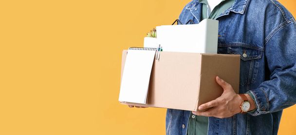 Dismissed man holding box with personal things on yellow background with space for text - Fotoğraf, Görsel