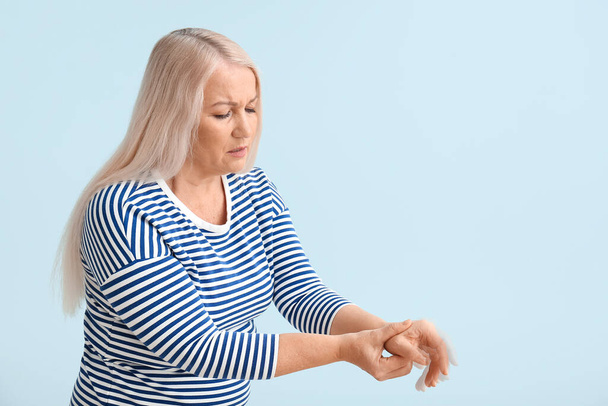 Mujer madura con síndrome de Parkinson sobre fondo azul claro - Foto, imagen