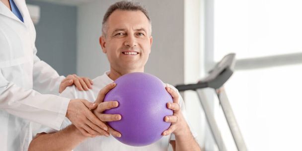 Paciente maduro haciendo ejercicios con pelota en centro de rehabilitación - Foto, Imagen