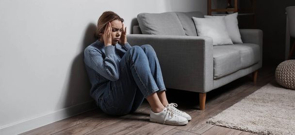 Депрессивная молодая женщина сидит на полу дома - Фото, изображение