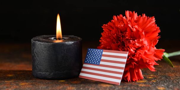 Burning candle, USA flag and flower on dark background. National Day of Prayer and Remembrance for the Victims of the Terrorist Attacks - Photo, image