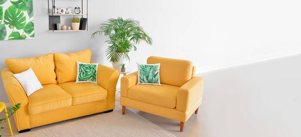 Interieur van stijlvolle woonkamer met gele bank en fauteuil - Foto, afbeelding