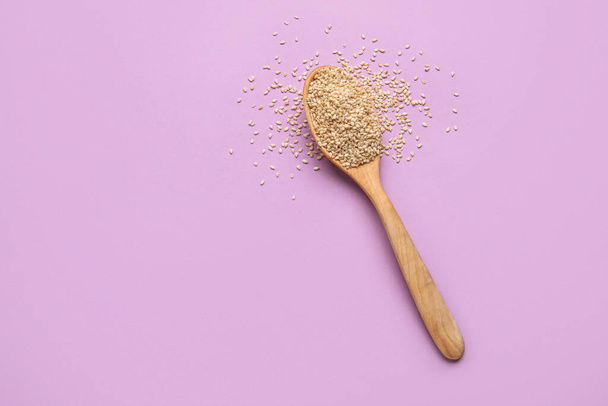 Wooden spoon with sesame seeds on color background - Photo, Image