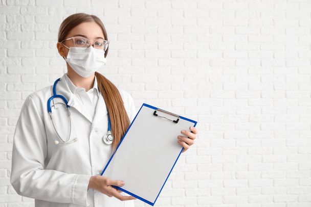 Vrouwelijke arts met blanco klembord op witte achtergrond - Foto, afbeelding