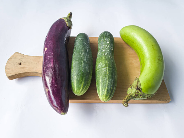 Raw vegetables consisting of purple green eggplant and cucumber - Valokuva, kuva
