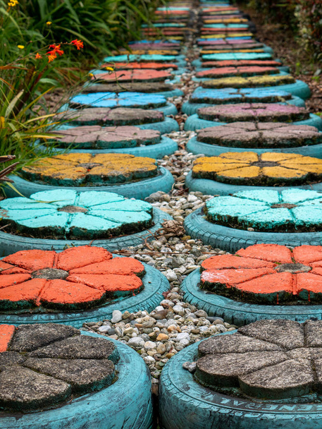 Дорога цемента Цветы различных цветов, сделанные с шинами - Фото, изображение