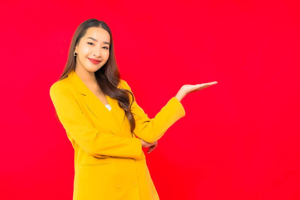 Porträt schöne junge Geschäft asiatische Frau lächeln mit Aktion auf rotem isolierten Hintergrund - Foto, Bild