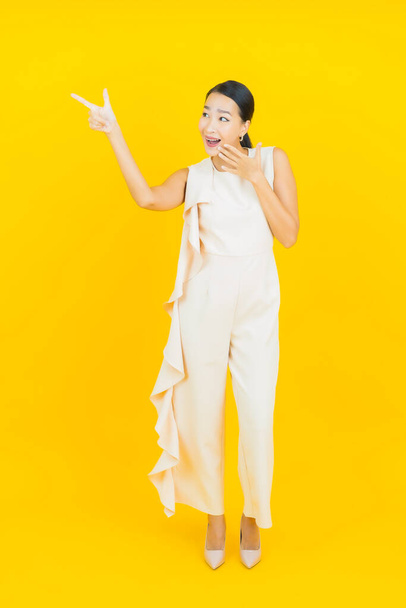 Portré gyönyörű fiatal ázsiai nő mosoly akció sárga színű háttér - Fotó, kép