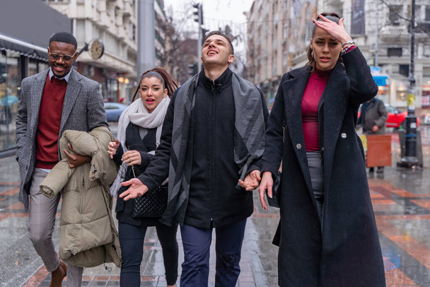 Vier multiethnische Geschäftemacher gehen zusammen auf dem Regen spazieren, während sie über das Geschäft reden, aus nächster Nähe - Foto, Bild