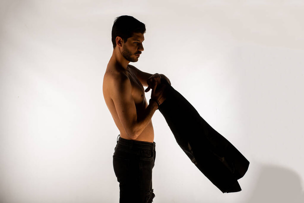 Un hombre guapo sin camisa haciendo poses frente a la cámara en el estudio - Foto, Imagen