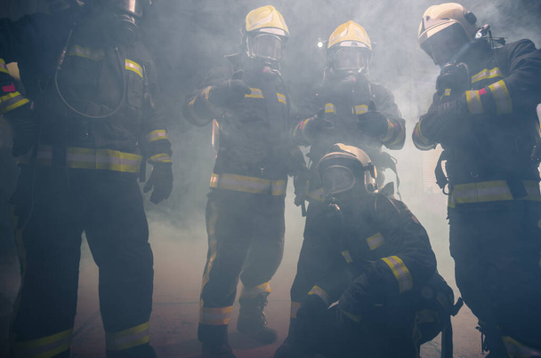 消防署内で消火器の煙の中に立つ消防士のチーム - 写真・画像