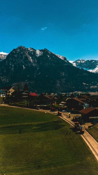 An aerial drone view of Kempten town surrounded by beautiful  Alpine mountains against a blue sky - Fotó, kép