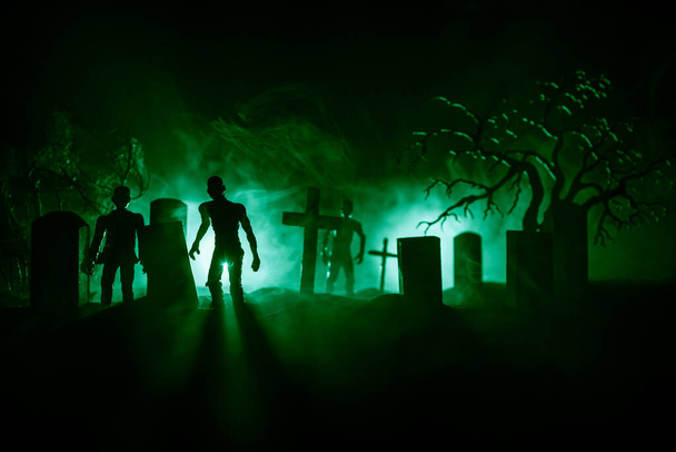 Eng uitzicht op zombies op kerkhof dode boom, maan, kerk en griezelige bewolkte hemel met mist, Horror Halloween concept. Selectieve focus - Foto, afbeelding