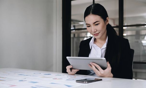 Jeune femme d'affaires asiatique travaille sur tablette avec ordinateur portable au bureau - Photo, image