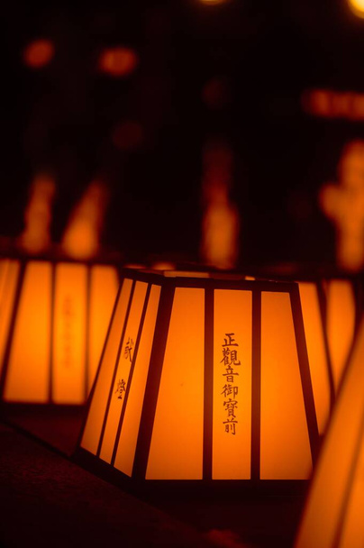 A vertical shot of beautiful Japanese lanterns arranged in rows and giving off light - Foto, Imagen