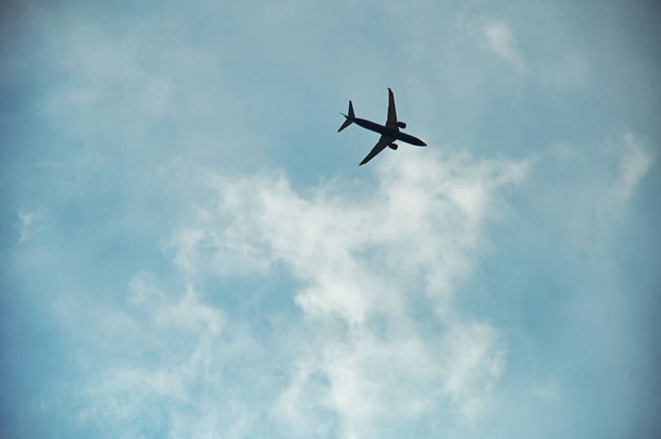A low angle shot of an airplane flying in the blue cloudy sky - Foto, Bild