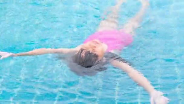 Happy little sisters are swimming and playing in outdoor swimming pool in a tropical resort during family summer vacation. Kids learning to swim. Healthy Summer Activities for Kids. - Πλάνα, βίντεο