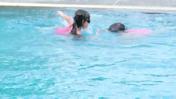 Happy little sisters are swimming and playing in outdoor swimming pool in a tropical resort during family summer vacation. Kids learning to dive and swim. Healthy Summer Activities for Kids. - Filmagem, Vídeo